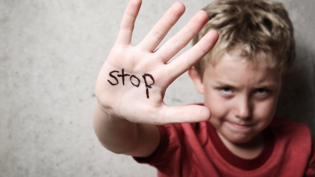 Photo of child with stop written on his hand